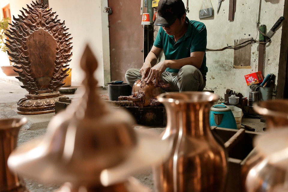 Nghệ nhân tỉ mỉ chạm khắc từng đường nét tinh xảo cho sản phẩm đồng đúc. (Ảnh: Minh Quyết/TTXVN)