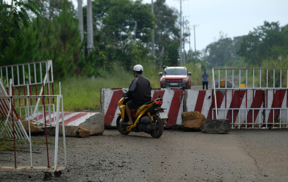 Người dân điều khiển phương tiện lách qua rào chắn của cơ quan chức năng trên tuyến đường tránh cấm lưu thông phía Nam thành phố Bảo Lộc. (Ảnh: Nguyễn Dũng/TTXVN)