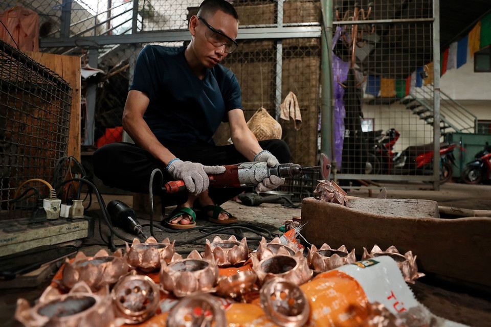 Sản phẩm sau khi đúc xong được người thợ làm bóng, hoàn thiện thủ công qua các công đoạn. (Ảnh: Minh Quyết/TTXVN)