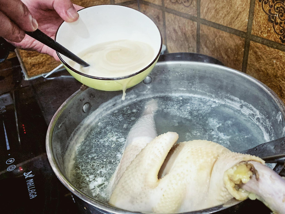 Pha các loại gia vị đường, muối, mì chính, hạt nêm vào nước dùng luộc gà. (Ảnh: Mai Mai/Vietnnam+)