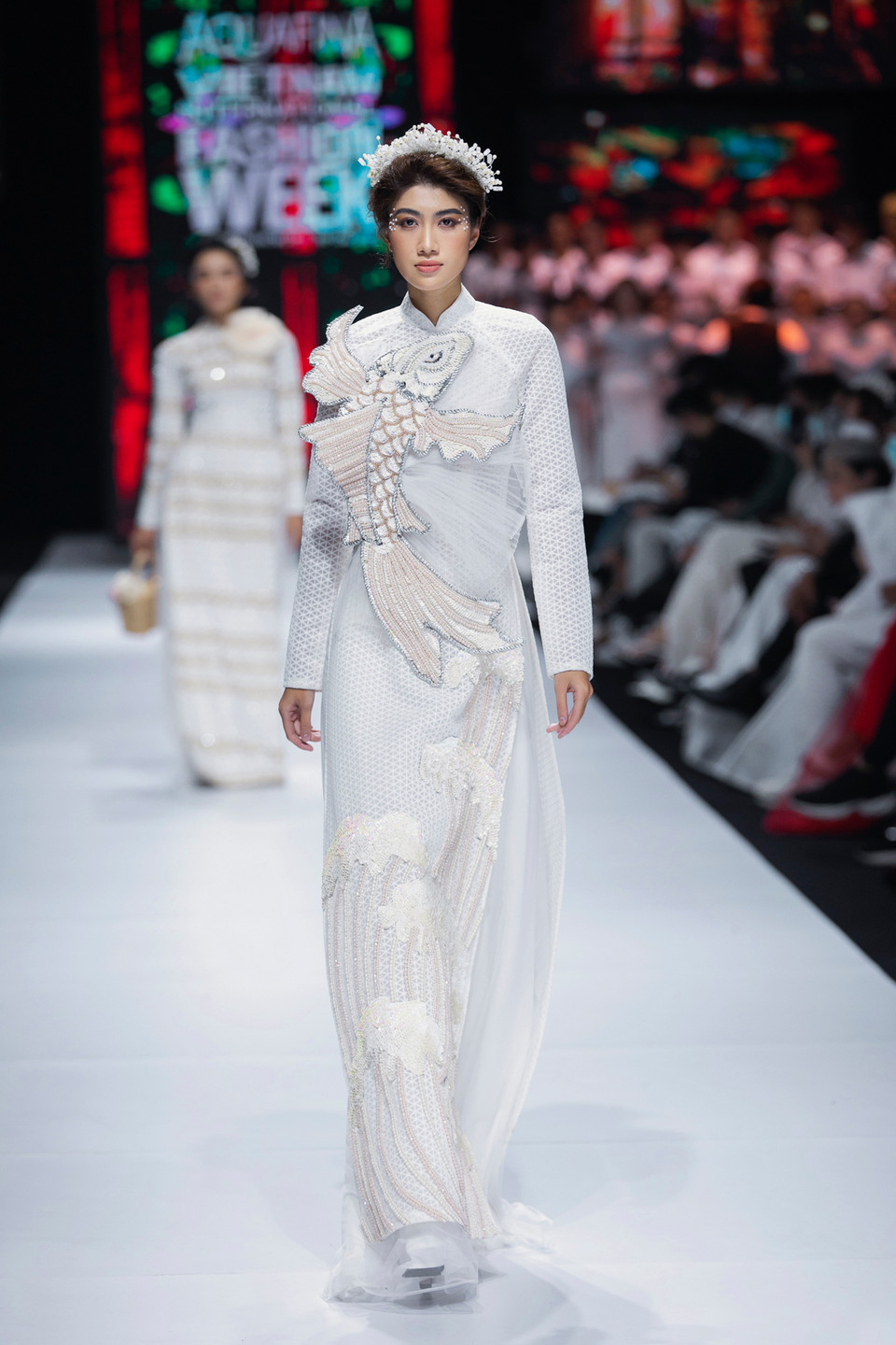 Cá chép - một linh vật trong văn hóa Việt Nam cũng được xuất hiện làm điểm nhấn trên tà áo dài trắng. (Ảnh: CTV/Vietnam+)