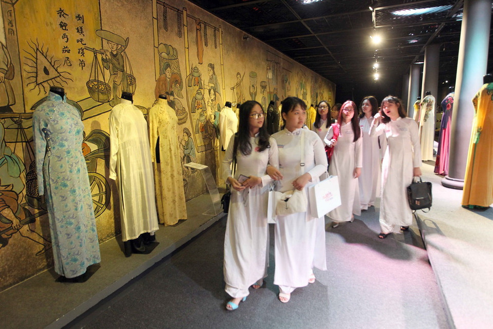 Các em học sinh xem các mẫu áo dài tại triển lãm 'Duyên dáng Áo dài Thành phố Hồ Chí Minh.' (Ảnh: Quang Nhựt/TTXVN)