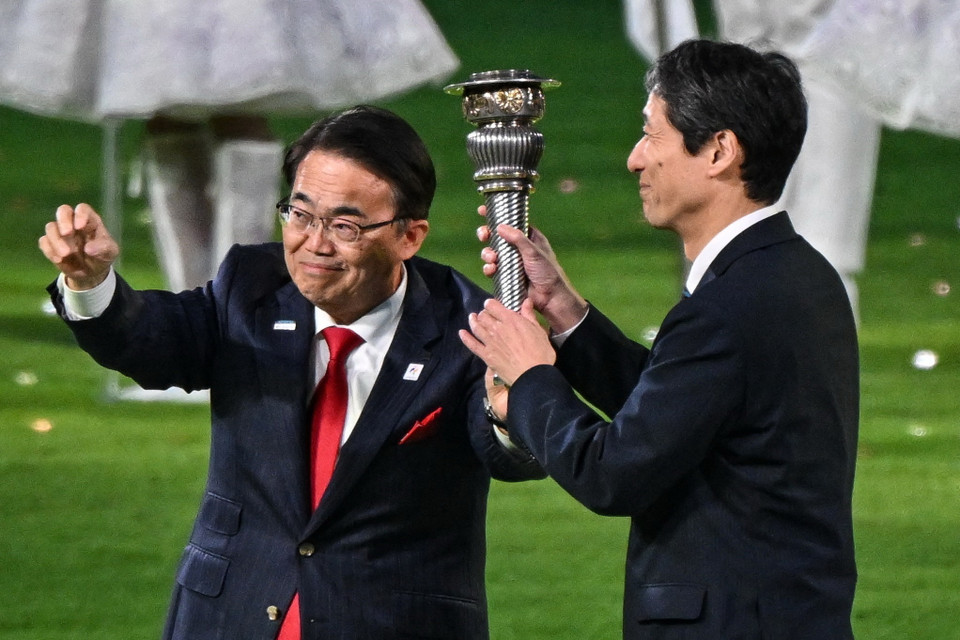 Đại diện của Nhật Bản - chủ nhà ASIAD 20 - nhận chuyển giao ngọn đuốc tại Lễ Bế mạc. (Ảnh: AFP/TTXVN)