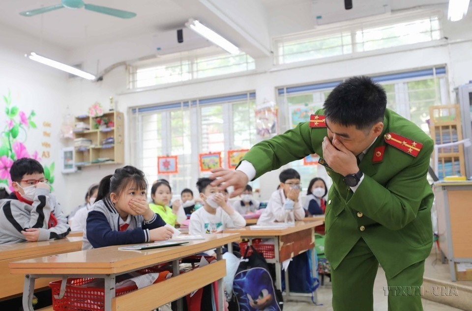 Công an quận Ba Đình (Hà Nội) hướng dẫn học sinh phòng tránh khói độc và cách di chuyển ra khỏi lớp khi có đám cháy xảy ra. (Ảnh: Thanh Tùng/TTXVN)