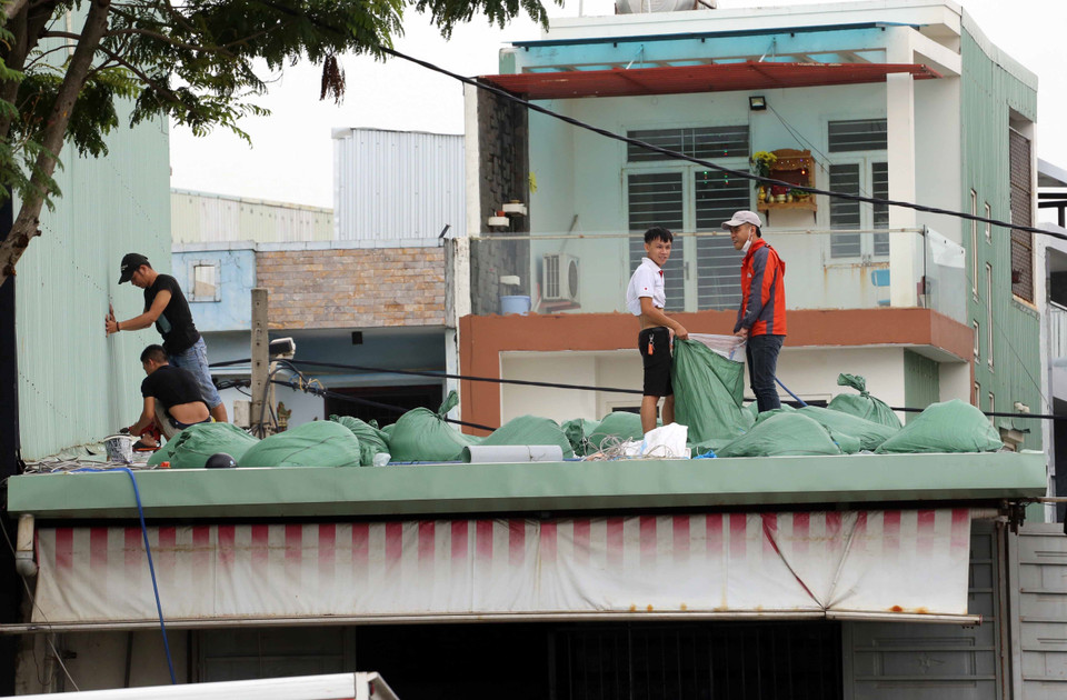 Người dân Đà Nẵng khẩn trương chèn mái tôn nhà bằng các bao nước để ứng phó với bão số 4.(Ảnh: Trần Lê Lâm/TTXVN)