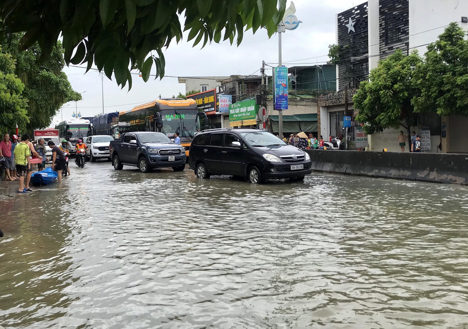 Các chủ phương tiện điều khiển xe ôtô đi vào sát giữa tim đường, chậm rãi đi qua đoạn đường ngập. (Ảnh: Văn Tý/TTXVN)