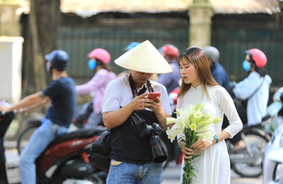 Các bạn trẻ tranh thủ ra đường ghi lại những khoảnh khắc đẹp nhưng vẫn cần chú ý đeo khẩu trang nơi công cộng. (Ảnh: Thành Đạt/TTXVN)