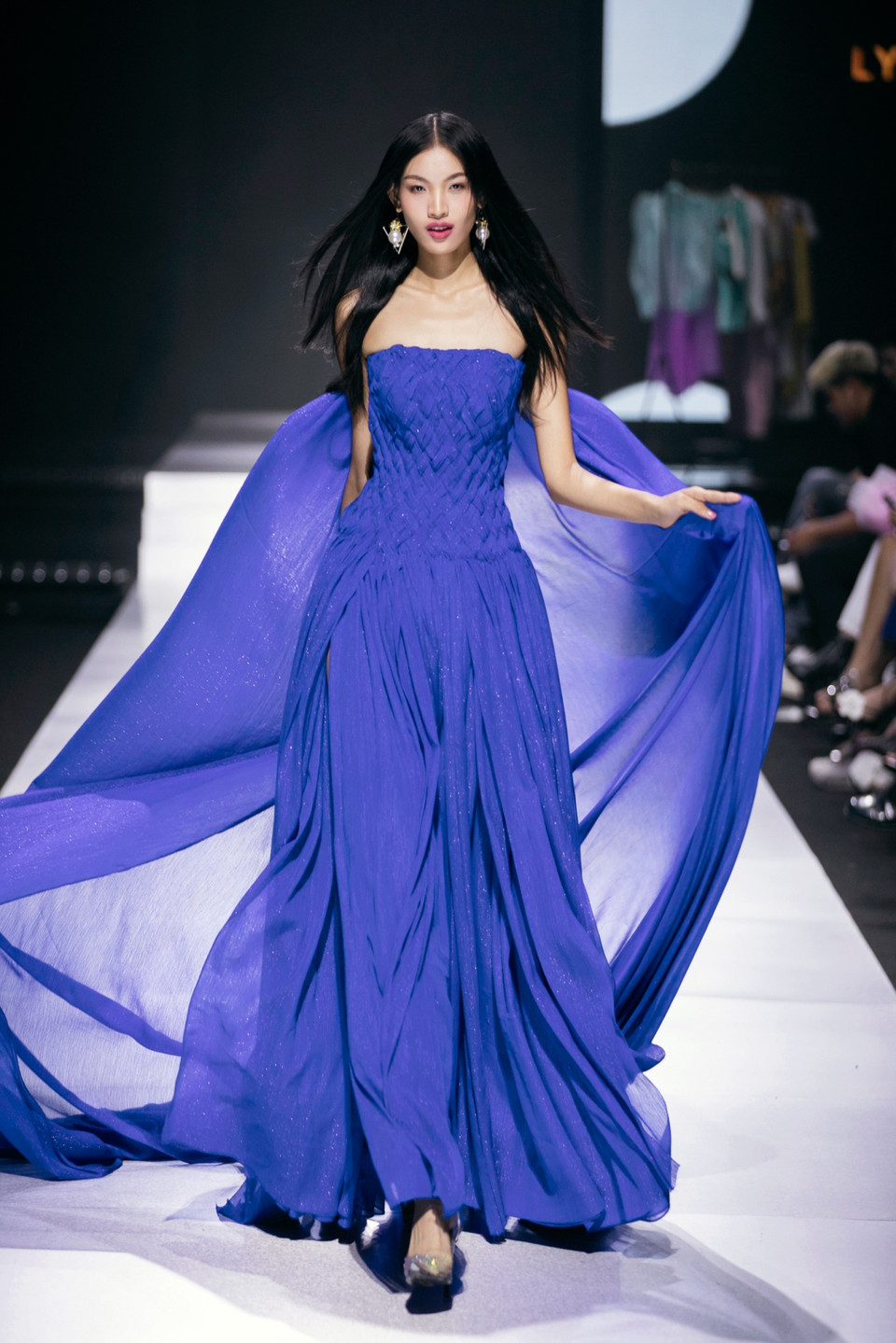 Được Lý Giám Tiền “chọn mặt gửi vàng” cho vị trí mở màn, Quán quân The Face Vietnam Huỳnh Tú Anh đẹp tựa nữ thần khi xuất hiện nổi bật, thu hút mọi ánh nhìn trên sàn diễn. Trong thiết kế cúp ngực lấp lánh kết hợp cùng áo choàng dài “tone sur tone” xanh coban, Tú Anh kiêu sa trong từng bước đi uyển chuyển mở màn cho bộ sưu tập. (Ảnh: CTV/Vietnam+)