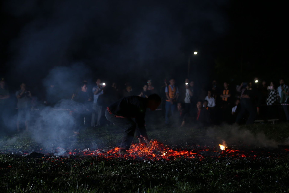 Những diễn viên sau khi được thầy cúng làm lễ nhập vai nhảy lửa, sẽ dùng tay dập tắt đống than đang cháy rực mà không bị bỏng. (Ảnh: Quý Trung/TTXVN)