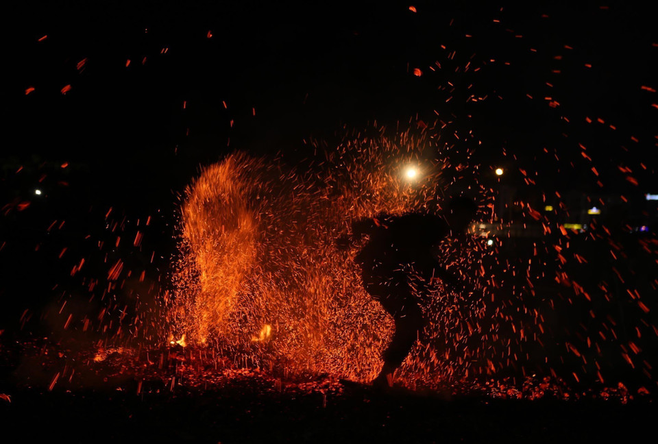 Những diễn viên sau khi được thầy cúng làm lễ nhập vai nhảy lửa, để dập tắt đống than đang cháy rực nhưng không bị bỏng. (Ảnh: Quý Trung/TTXVN)