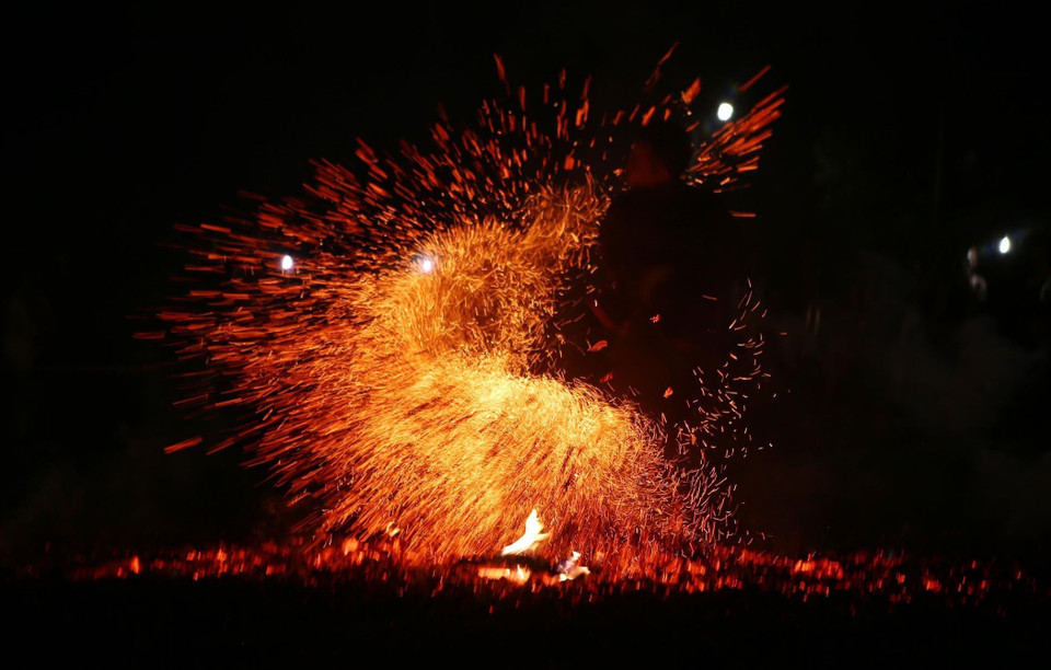 Sau khi nghệ nhân Thầy cúng làm lễ xong các diễn viên với đôi chân trần nhảy vào đống than hồng nhưng không hề bị bỏng.(Ảnh: Quý Trung/TTXVN)