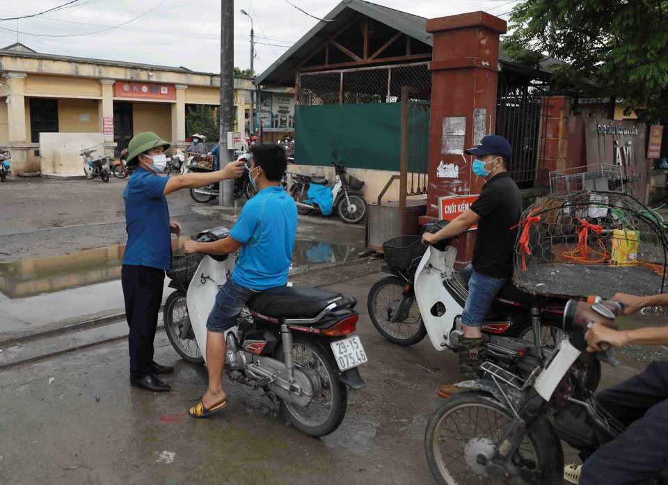 Đo thân nhiệt cho tất cả các người vào chợ. (Ảnh: Vũ Sinh/TTXVN)