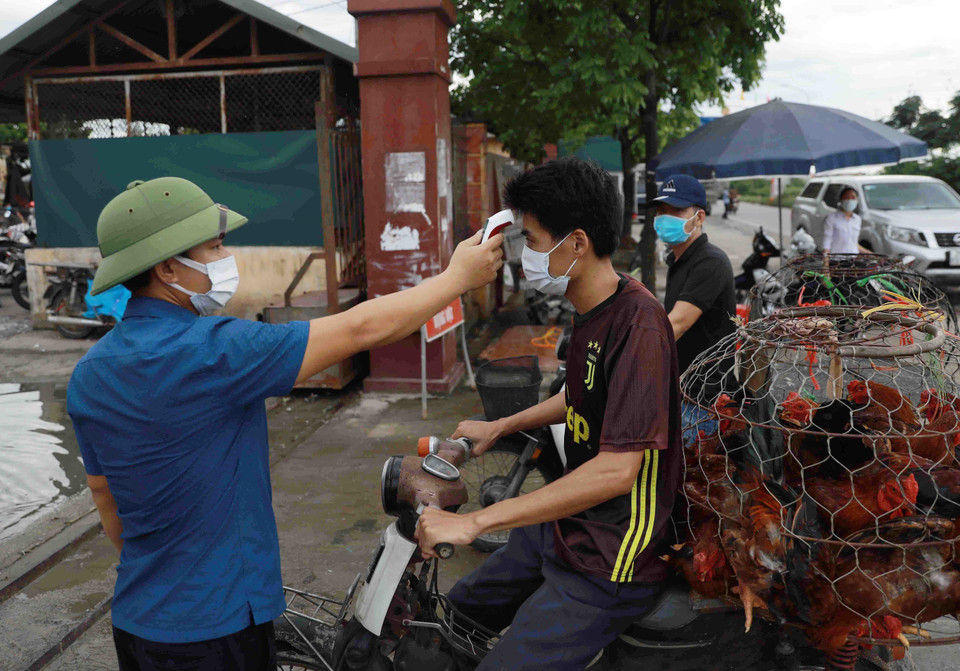 Ban quản lý chợ Hà Vĩ tổ chức đo thân nhiệt cho tất cả các dân vào chợ. (Ảnh: Vũ Sinh/TTXVN)