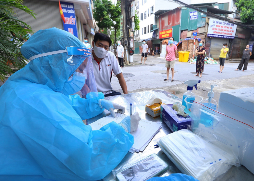 Nhân viên y tế lấy thông tin người dân trước khi lấy mẫu. (Ảnh: Hoàng Hiếu/TTXVN)