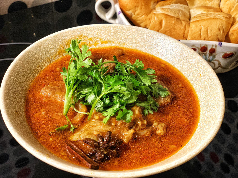 Cuối cùng cho tương cà cùng muỗng rượu vang đỏ vào, đun thêm 1 phút cho nồi bò sánh mịn rồi nêm thêm gia vị vừa miệng. Múc ra bát cùng chút rau mùi và thưởng thức với bánh mỳ hoặc cơm nóng. (Ảnh: Mai Mai/Vietnam+)