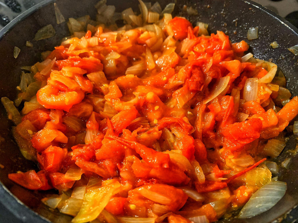 Trong lúc đợi thịt bò ướp, phi hành tây với cà chua cho chín mềm. (Ảnh: Mai Mai/Vietnam+)