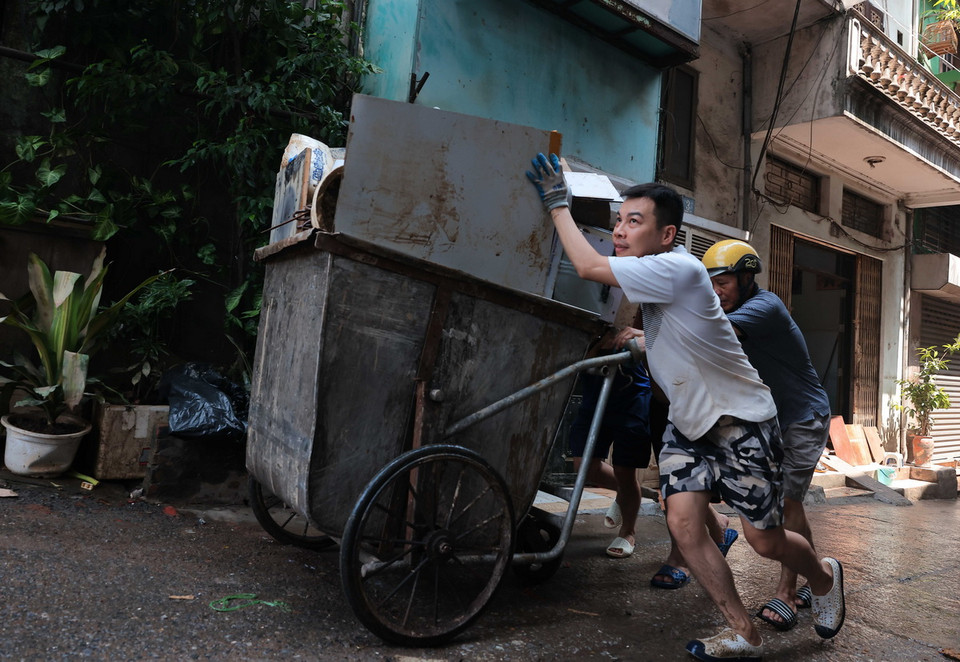 Cùng chung sức vận chuyển đồ đạc bị hư hỏng do ngập nước đến nơi tập kết. (Ảnh: Hoàng Hiếu/TTXVN)