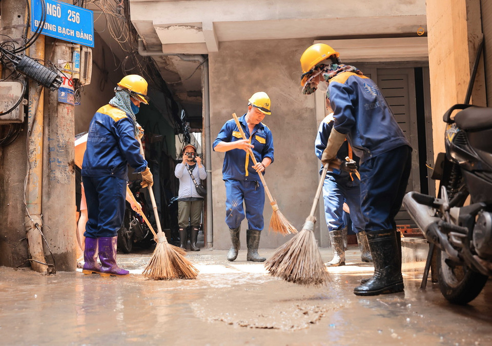Người dân và nhân viên Công ty thoát nước Hà Nội quét dọn, làm sạch khu vực bị ngập ở phường Chương Dương trưa 14/9. (Ảnh: Hoàng Hiếu/TTXVN)