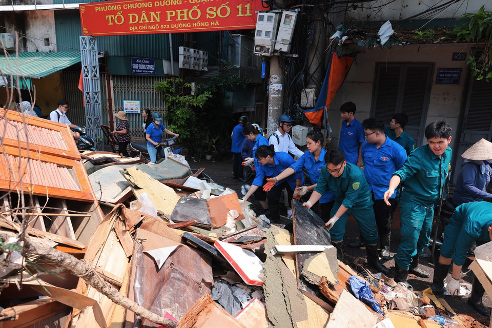 Lực lượng dân quân tự vệ, thanh niên tình nguyện hỗ trợ thu gọn, vận chuyển đồ đạc bị hư hỏng của người dân sáng 14/9. (Ảnh: Hoàng Hiếu/TTXVN)