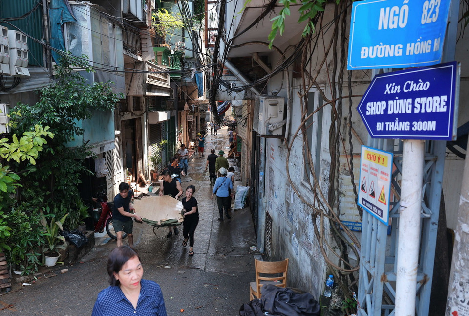 Người dân ngõ 823 đường Hồng Hà chung sức dọn dẹp vệ sinh nhà cửa, vận chuyển đồ đạc bị hư hỏng ra nơi tập kết để vận chuyển đi. (Ảnh: Hoàng Hiếu/TTXVN)