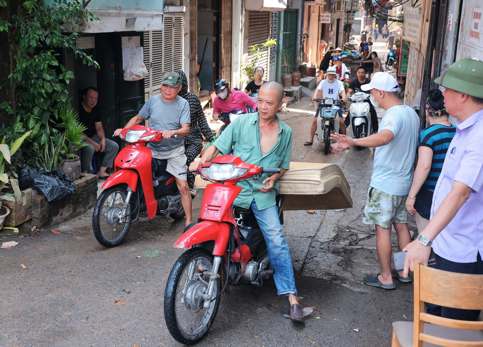 Người dân ngõ 823 đường Hồng Hà tích cực dọn dẹp nhà cửa, vận chuyển đồ đạc bị hư hỏng đến nơi tập kết. (Ảnh: Hoàng Hiếu/TTXVN)