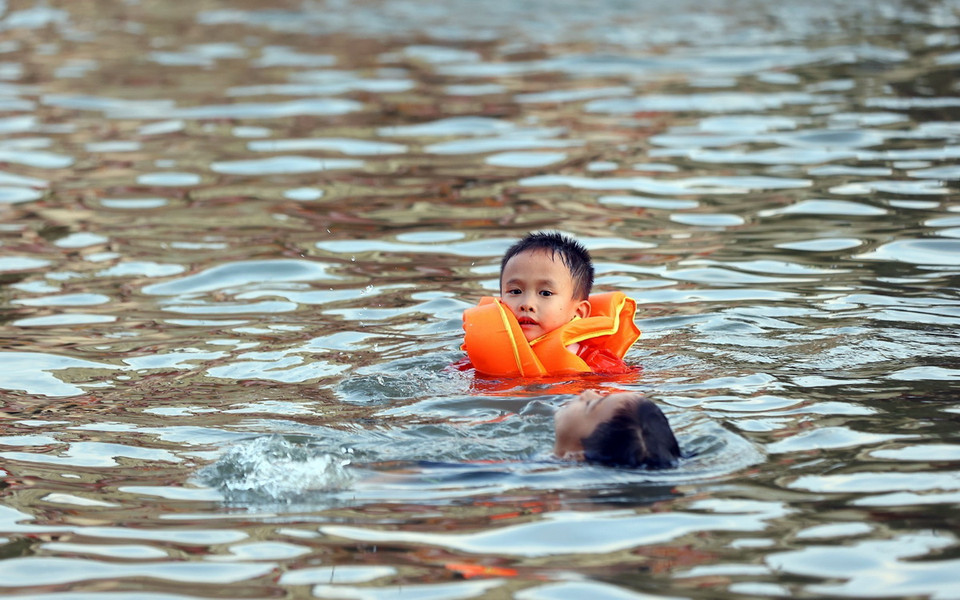Suốt một tuần qua, tận dụng khoảng không gian cánh đồng, đường làng, sân nhà văn hóa bị ngập nước, hằng ngày, người dân xã Cấn Hữu vẫn cho trẻ nhỏ tập bơi. (Ảnh: Huy Hùng/TTXVN)