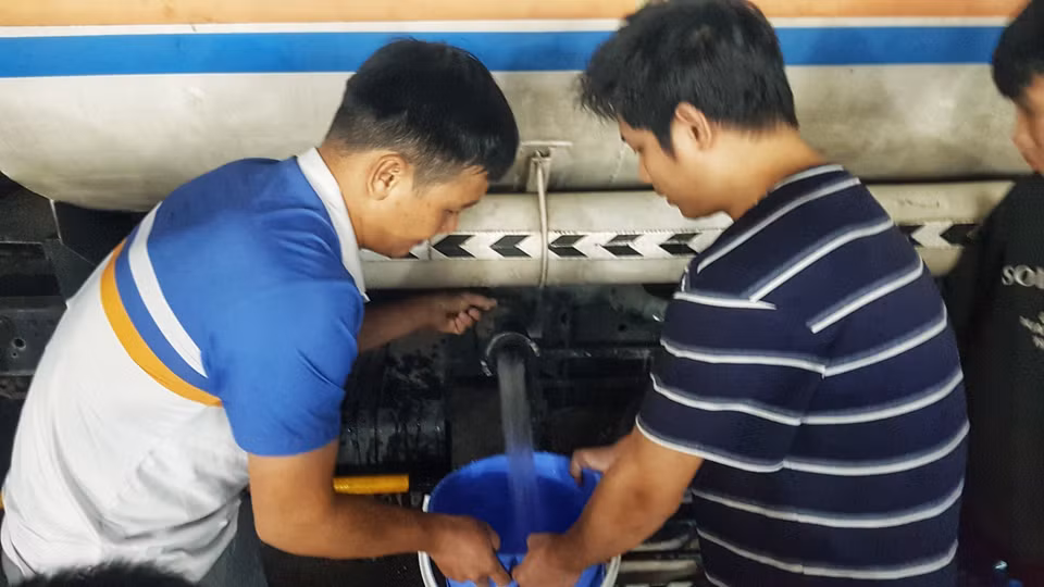 Người dân Khu Đô thị Thanh Hà lấy nước từ xe chở nước sạch. (Ảnh: Hoàng Hiếu/TTXVN)