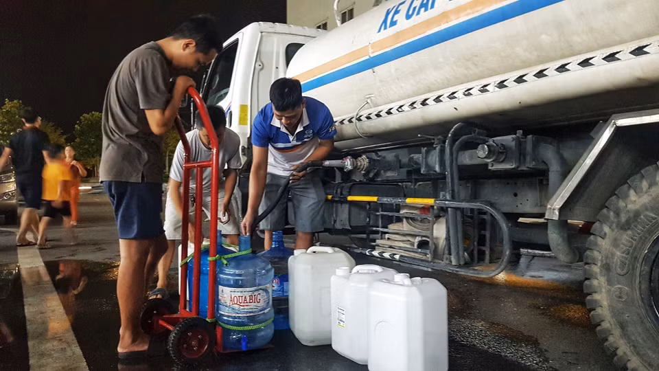 Người dân Khu Đô thị Thanh Hà tận dụng mọi vật chứa và phương tiện để vận chuyển nước về gia đình. (Ảnh: Hoàng Hiếu/TTXVN)