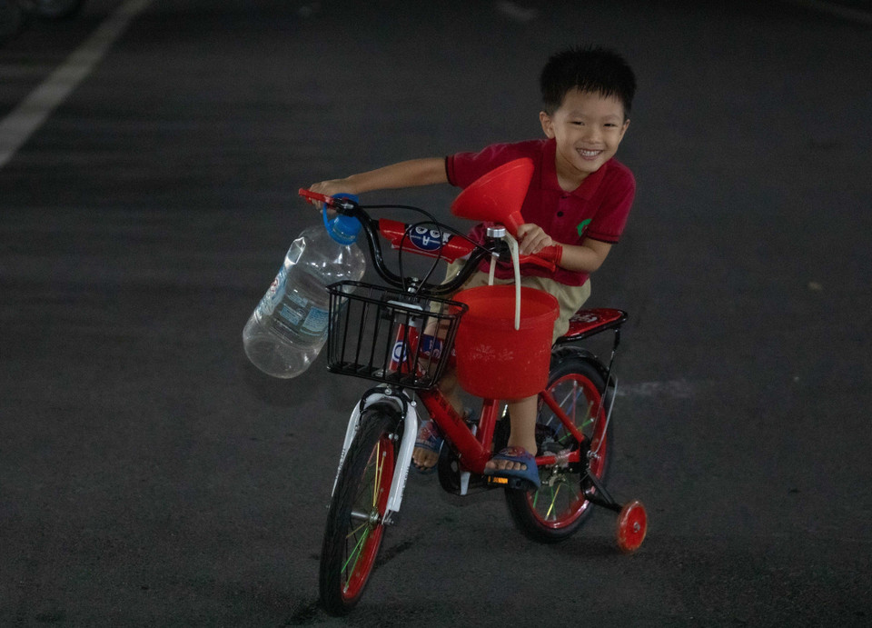 Một trẻ nhỏ với bình, xô, phễu để lấy nước cho gia đình. (Ảnh: Hoàng Hiếu/TTXVN)