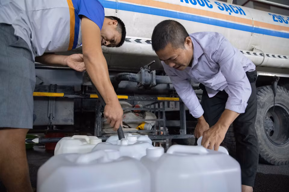 Người dân chứa nước vào can để đưa lên nhà. (Ảnh: Hoàng Hiếu/TTXVN)