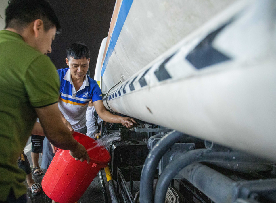 Người dân khu đô thị Thanh Hà lấy nước từ xe téc về sinh hoạt. (Ảnh: Hoàng Hiếu/TTXVN)