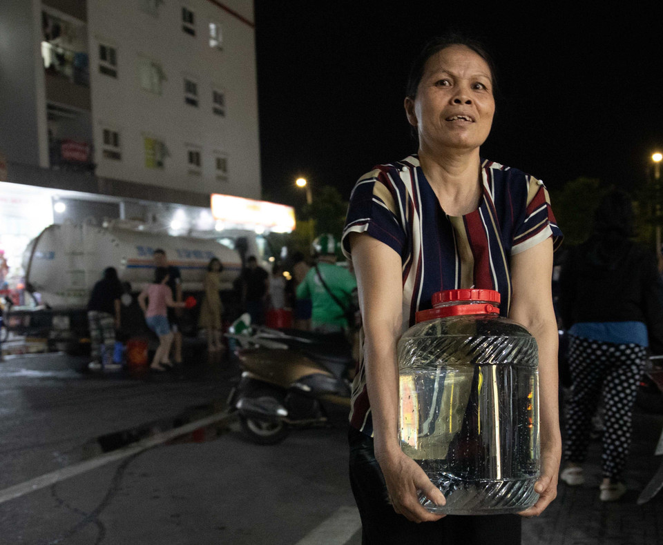 Người dân khu đô thị Thanh Hà tận dụng mọi vật dụng sẵn có để lấy nước từ xe về gia đình. (Ảnh: Hoàng Hiếu/TTXVN)