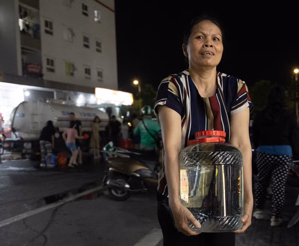 Người dân khu đô thị Thanh Hà tận dụng mọi vật dụng sẵn có để lấy nước từ xe về gia đình. (Ảnh: Hoàng Hiếu/TTXVN)