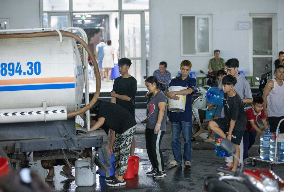 Người dân tòa HH2E và HH2D Khu Đô thị Thanh Hà xếp hàng chờ lấy nước. (Ảnh: Hoàng Hiếu/TTXVN)
