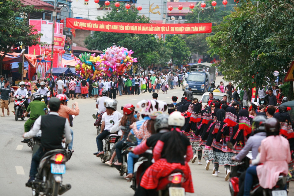 Các nam, nữ thanh niên người Dao Tiền mặc trang phục dân tộc đi diễu hành khắp thị trấn giữa hàng vạn du khách đổ về Mộc Châu. (Ảnh:Xuân Mai/Vietnam+)