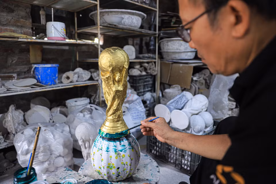 Ông Nhật đang hoàn thiện phần đế của chiếc cúp vàng World Cup 2022 với một lớp sơn màu xanh lá cây. (Ảnh: Việt Anh/Vietnam+)