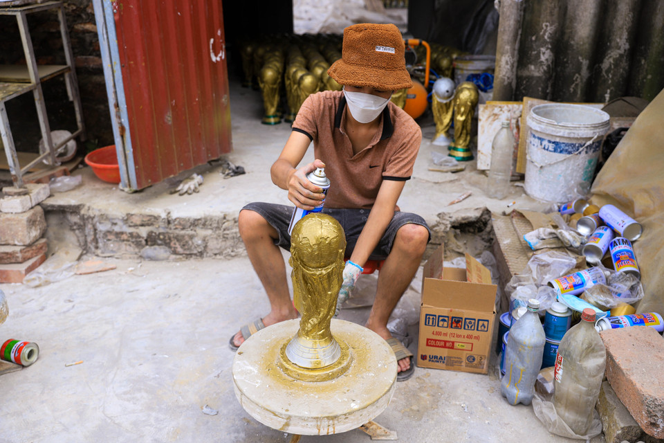 Sau khi sơn một lớp màu nhũ, người thợ Bát Tràng sẽ phủ lên một lớp sơn bóng để các đường nét của sản phẩm thêm nổi bật, tạo ra hiệu ứng giống với phiên bản cúp World Cup thật. (Ảnh: Việt Anh/Vietnam+)