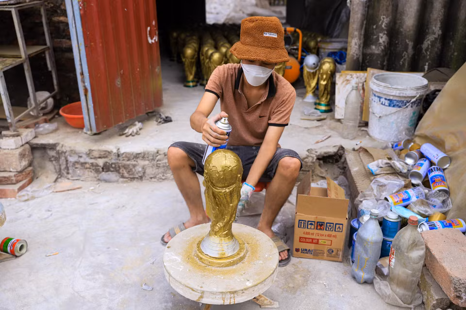 Sau khi sơn một lớp màu nhũ, người thợ Bát Tràng sẽ phủ lên một lớp sơn bóng để các đường nét của sản phẩm thêm nổi bật, tạo ra hiệu ứng giống với phiên bản cúp World Cup thật. (Ảnh: Việt Anh/Vietnam+)