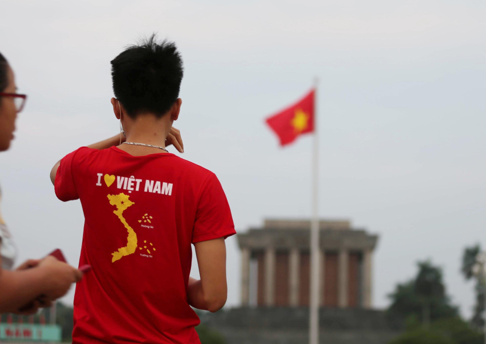 Một thanh niên mặc áo in hình Tổ quốc, ngắm nhìn lá Quốc kỳ trên Quảng trường Ba Đình sáng 2/9. (Ảnh: Văn Nam/TTXVN)