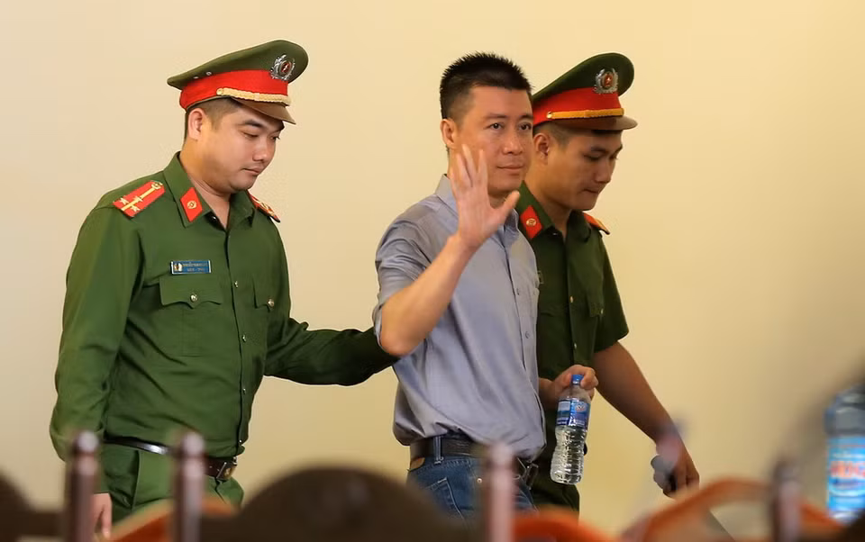 Lực lượng chức năng dẫn giải bị cáo Phan Sào Nam vào tòa. (Ảnh: Trung Kiên/TTXVN)