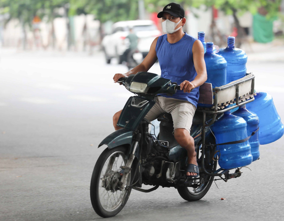 Nhân viên giao hàng không đội mũ bảo hiểm khi di chuyển trên phố. (Ảnh: Thanh Tùng/TTXVN)