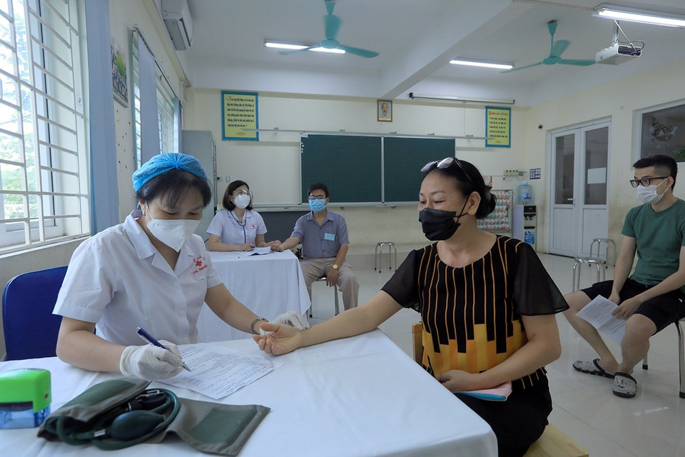 Nhân viên y tế phường Kim Giang khám sàng lọc cho người dân trước khi tiêm. (Ảnh: Phan Tuấn Anh/TTXVN)