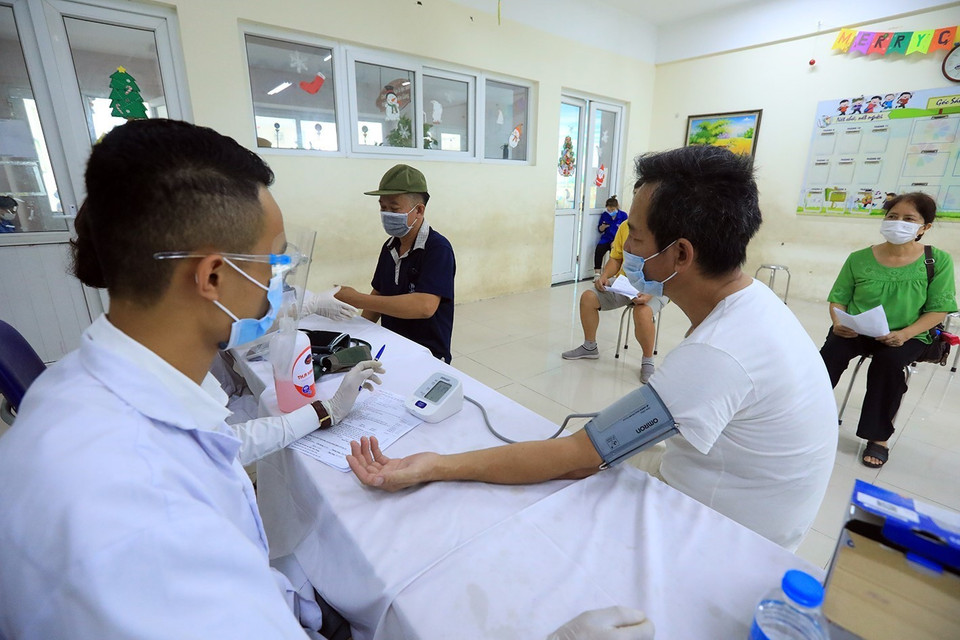 Nhân viên y tế đo huyết áp cho người dân trước khi tiêm. (Ảnh: Phan Tuấn Anh/TTXVN)