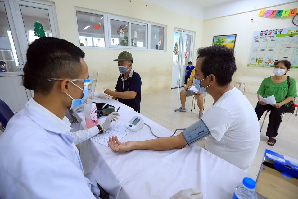 Nhân viên y tế đo huyết áp cho người dân trước khi tiêm. (Ảnh: Phan Tuấn Anh/TTXVN)