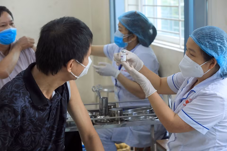 Nhân viên y tế phường Kim Giang giới thiệu loại vaccine tiêm được tiêm cho người dân. (Ảnh: Phan Tuấn Anh/TTXVN)