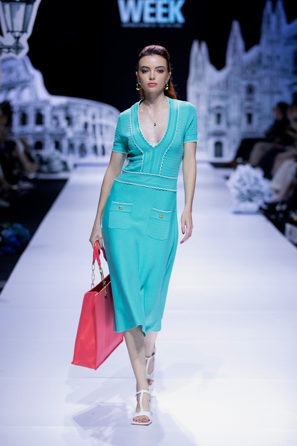 Thần thái người mẫu trong bộ váy mang hơi hướng cổ điển tông xanh ngọc, với phần cổ khoét sâu kết hợp cùng túi xách màu đỏ thu hút mọi ánh nhìn. (Ảnh: CTV)