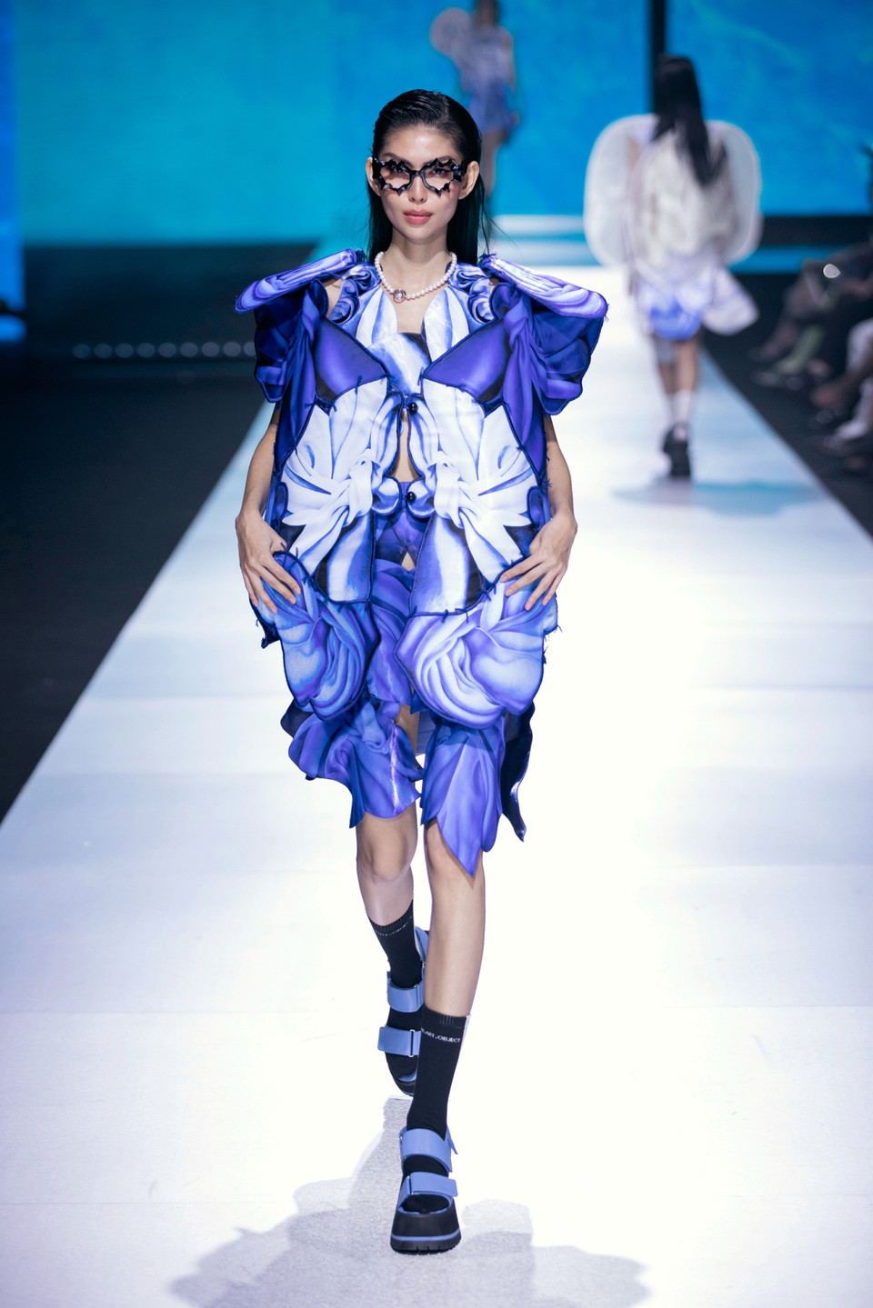 Chưa dừng lại ở đó, để tạo ấn tượng mạnh về thị giác, Võ Công Khanh đã sáng tạo các chất liệu được chọn lọc kỹ lưỡng bằng cách xử lý nhuộm, in, thêu, kết thủ công trên các họa tiết trước khi được dựng phom, đưa kỹ thuật xếp đặt các mảnh vải lồng ghép, đan xen nhau để tạo thành những cấu trúc 3D vô cùng tinh xảo và sống động. (Ảnh: CTV/Vietnam+)