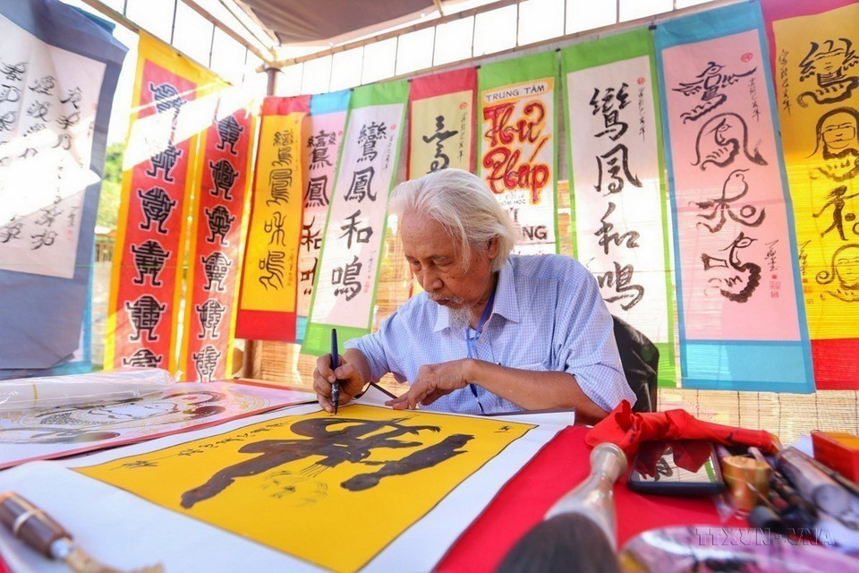 Nghệ nhân thư pháp Lê Thiên Lý viết chữ tại Festival bảo tồn và phát triển làng nghề Việt Nam năm 2023, nhằm bảo tồn, giữ gìn, tái hiện và phát huy bản sắc các giá trị truyền thống của làng nghề Việt Nam. (Ảnh: Tuấn Đức/TTXVN)