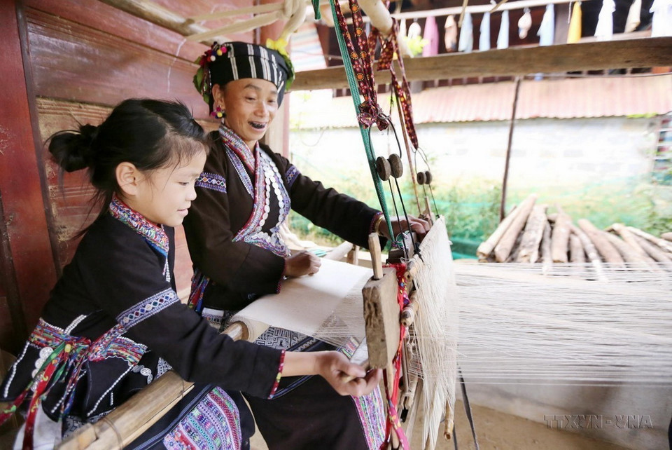 Trẻ em dân tộc Lự ở xã Bản Hon, huyện Tam Đường (Lai Châu) ngay từ khi còn nhỏ đã được tiếp cận với nghề dệt vải để may trang phục truyền thống từ những người phụ nữ cao tuổi. (Ảnh: Quý Trung/TTXVN)