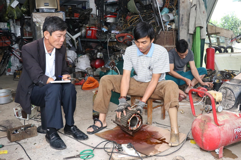 Nạn nhân bom mìn Trương Hồng Hoàn (sinh năm 1984), ở thôn Tây, xã Hiền Ninh, huyện Quảng Ninh, tỉnh Quảng Bình (giữa ảnh) vươn lên trong cuộc sống với nghề điện. (Ảnh: Anh Tuấn/TTXVN)